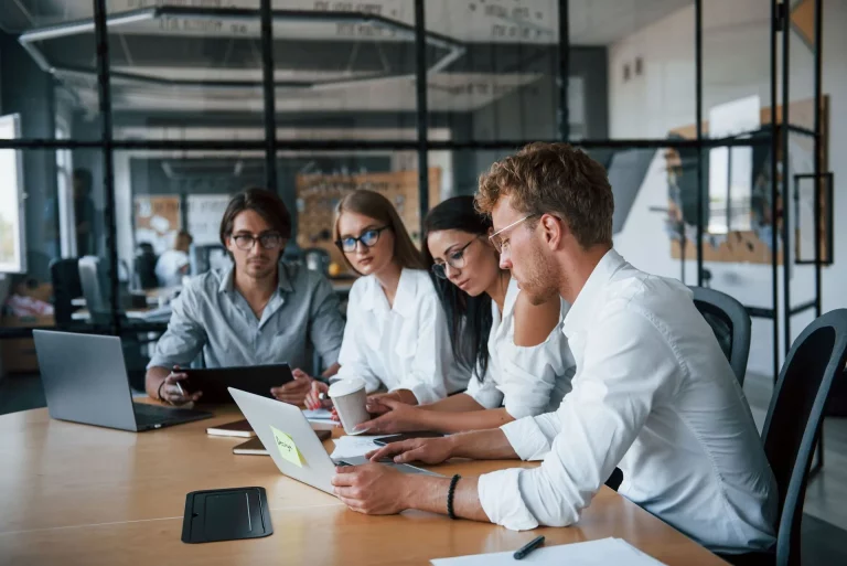 twee mannen en twee vrouwen bekijken iets op een laptop