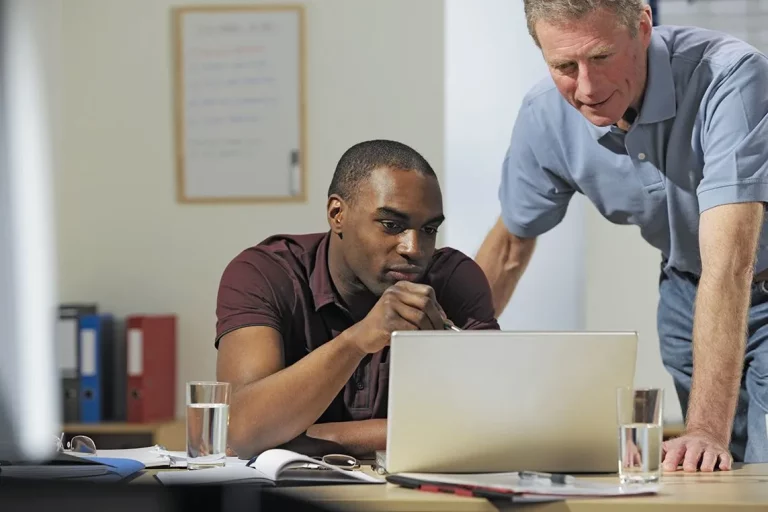 twee mannen die naar een laptop kijken