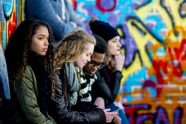 kinderen die tegen een muur met graffiti aan zitten