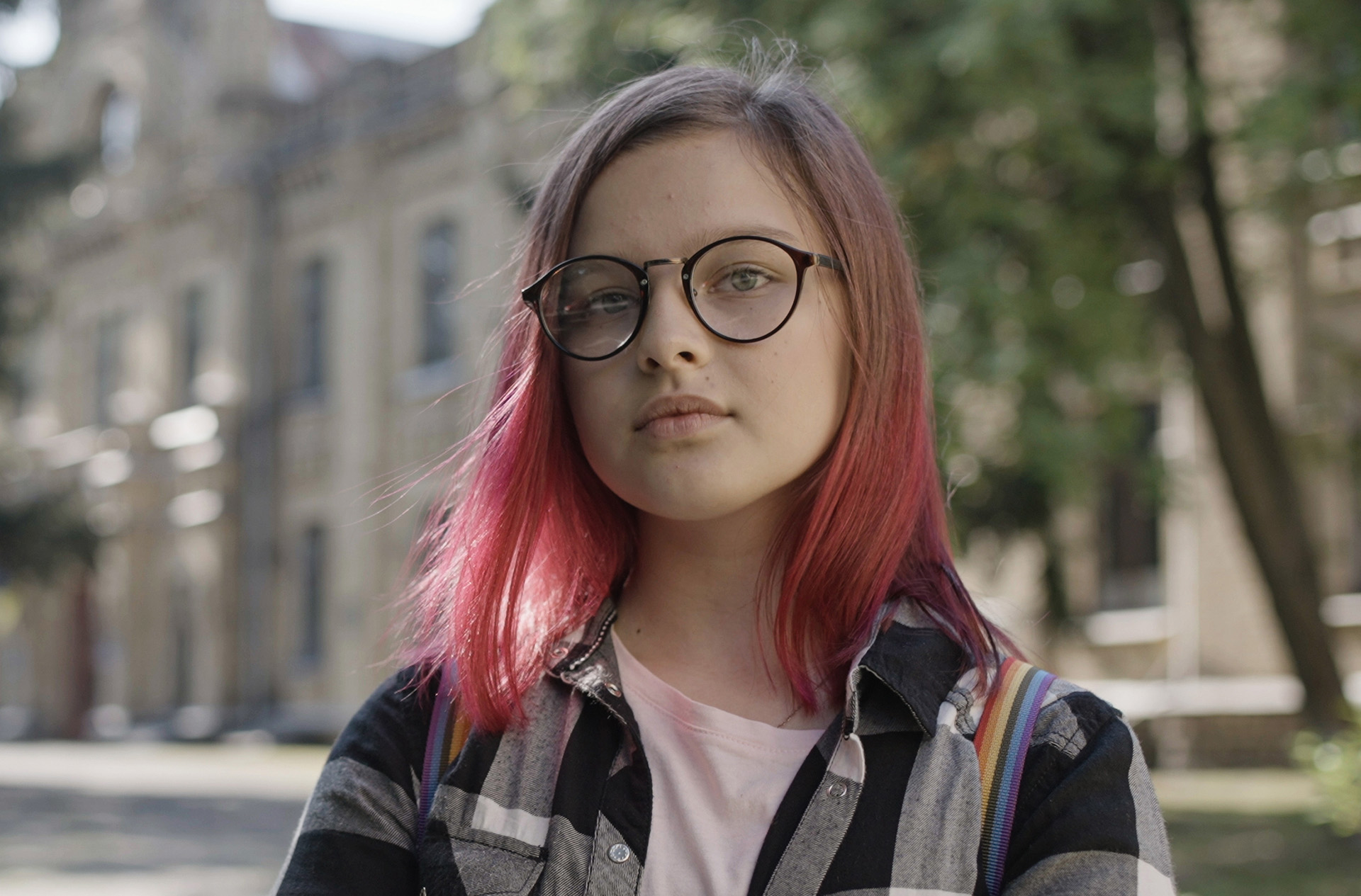 Stijlvol meisje met roze haar staat voor haar school.