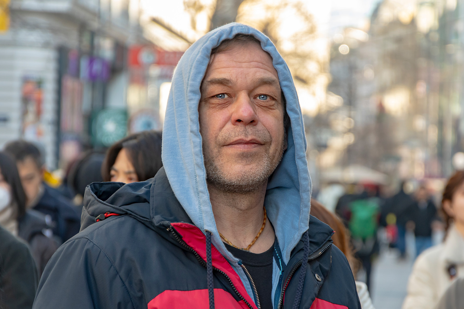 Een oudere man van 45-50 jaar oud op straat en een menigte mensen.