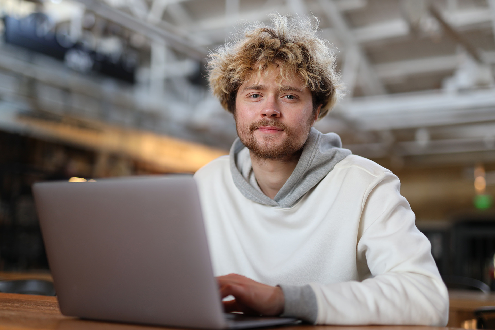 Jonge blonde man werkt achter een laptop op de werkplek.