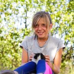 Meisje buiten met kat op schoot.