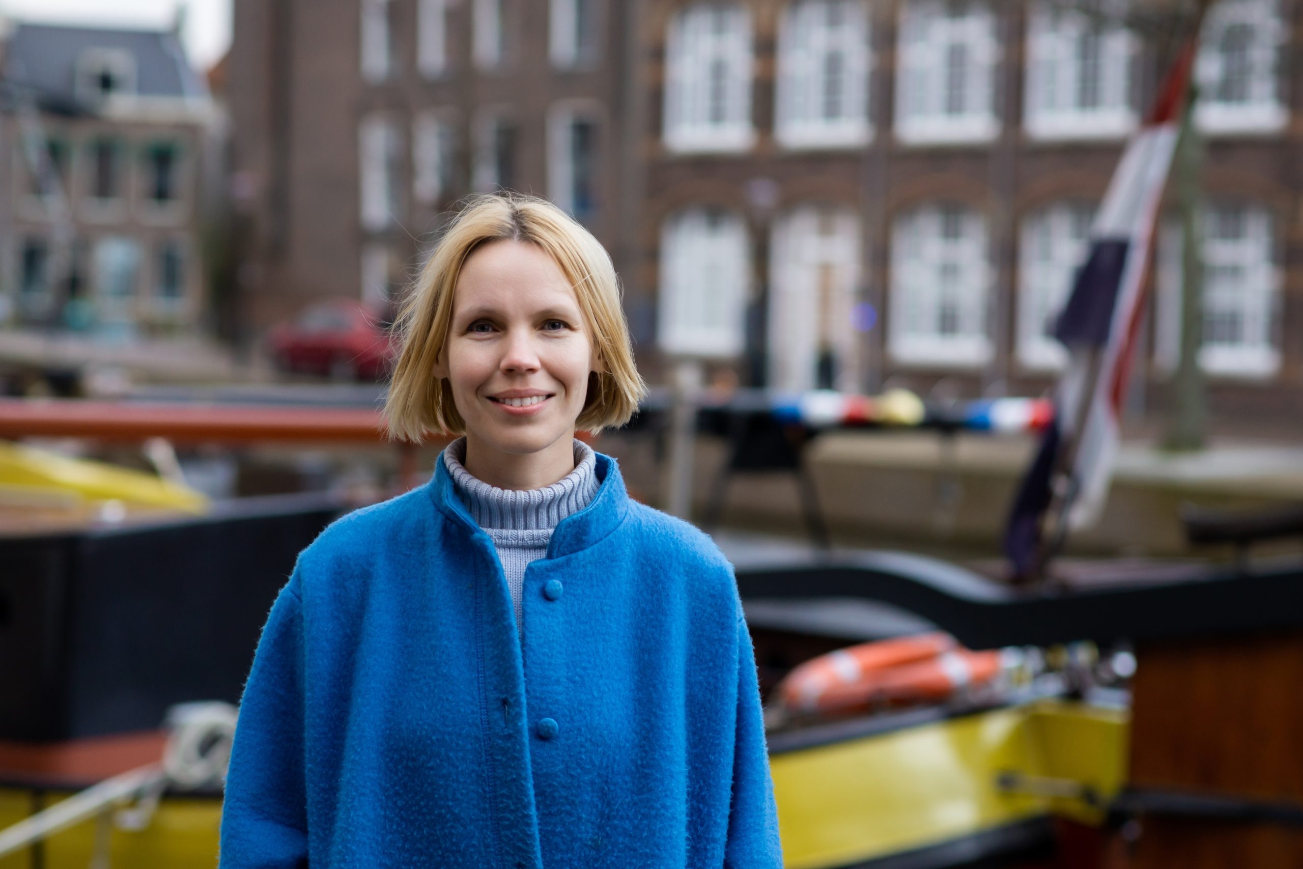 Adult,Woman,In,Coat,Smiling,While,Traveling,In,The,Netherlands.